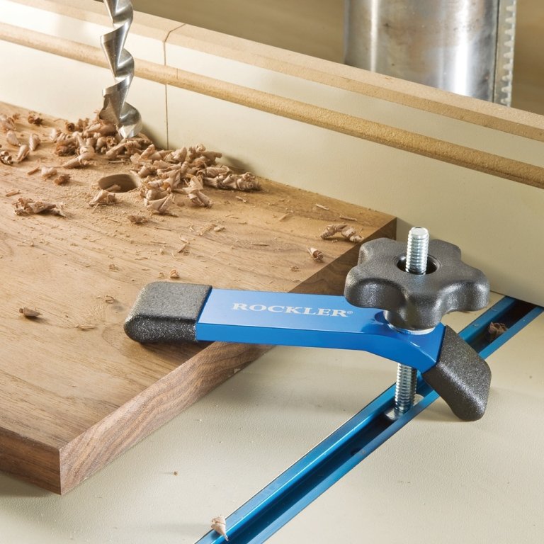 A Rockler Hold-Down Clamps holding a piece of wood in place for drilling