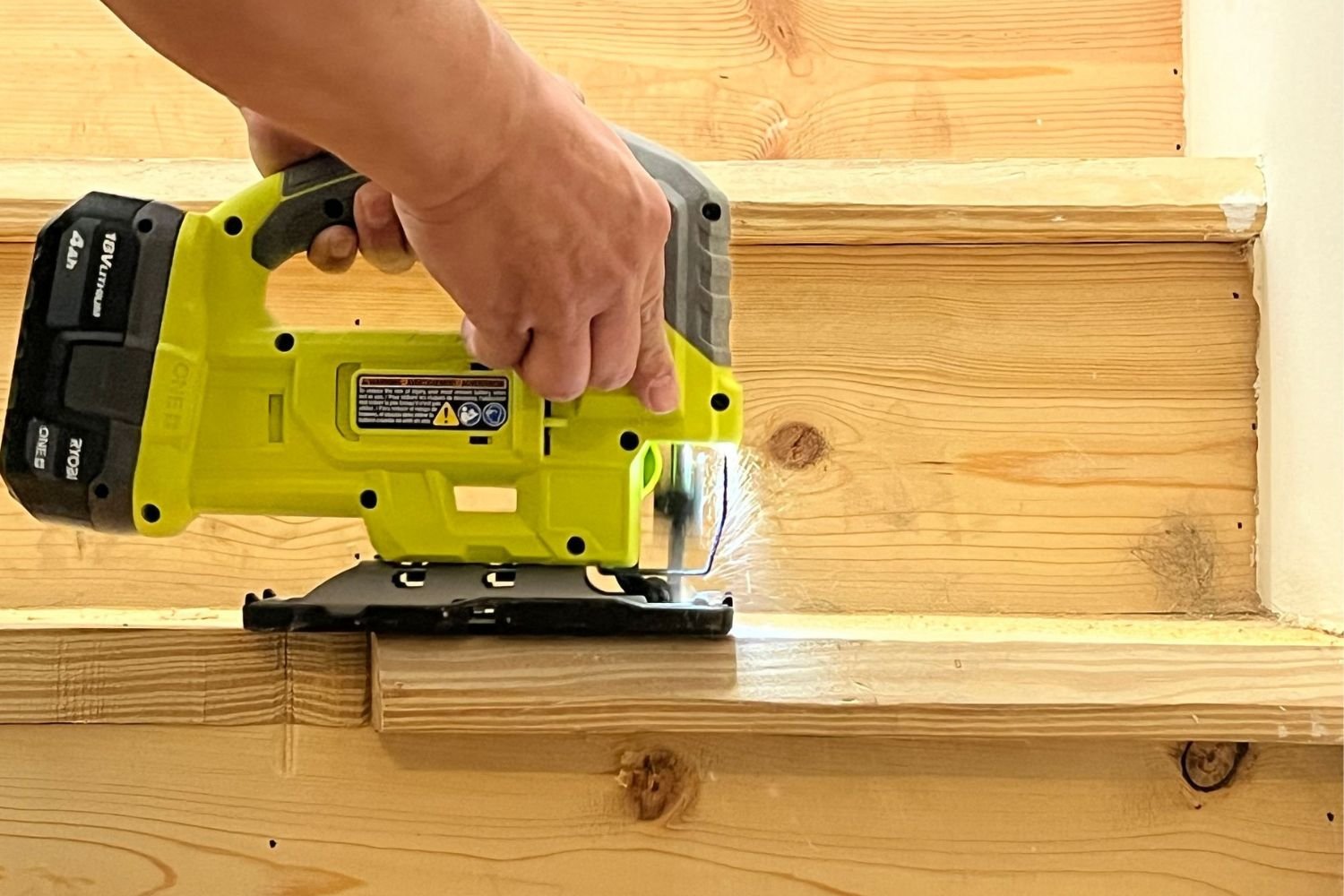 A person using the Ryobi random orbital sander to sand a staircase during testing