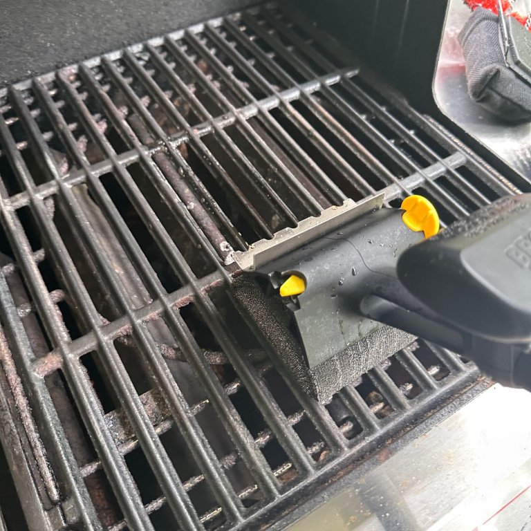 A product tester using the Scrub Daddy BBQ Daddy Grill Brush to clean a grill