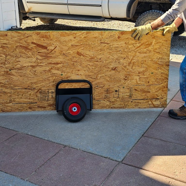 A person using the Home Depot Heavy-Duty Panel Dolly to move a large panel of MDF during testing
