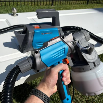 A product tester hodling the Tilswall Paint HVLP Sprayer in front of a painted cabinet door during testing