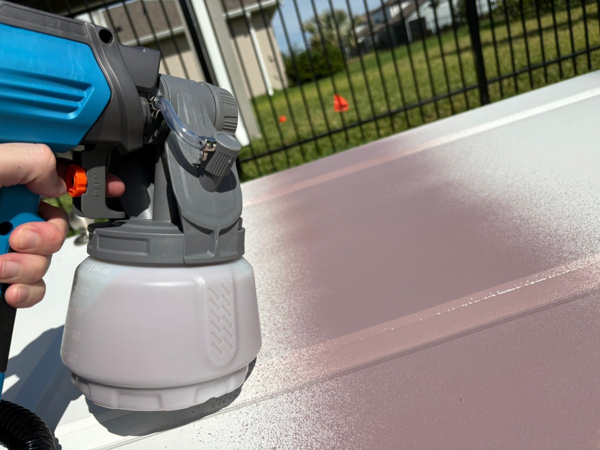 A product tester using the Tilswall Paint HVLP Sprayer to paint a cabinet door 