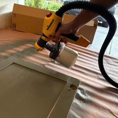 A product tester using the Wagner FLEXiO 5000 Stationary Paint Sprayer to paint a cabinet door
