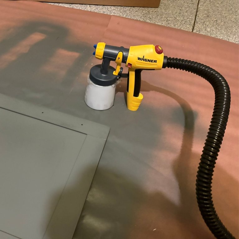A person using the Wagner FLEXiO 5000 Stationary Paint Sprayer to paint a cabinet door during testing