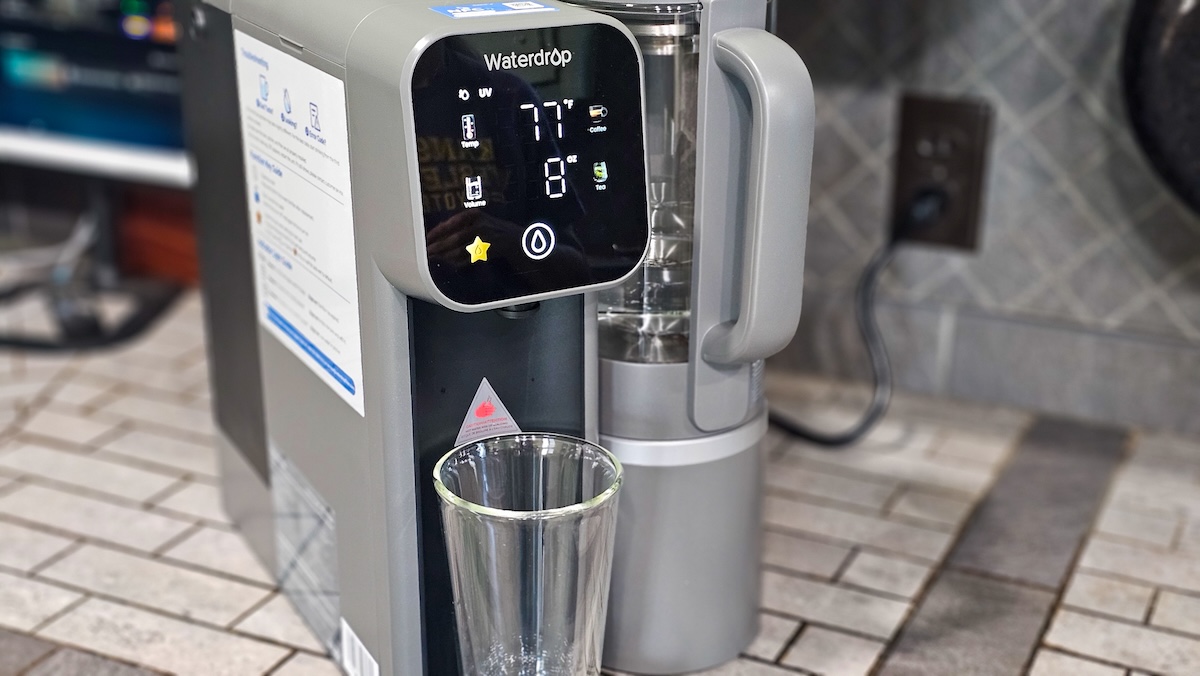 The Waterdrop M6H on the counter with a glass in place for dispensing