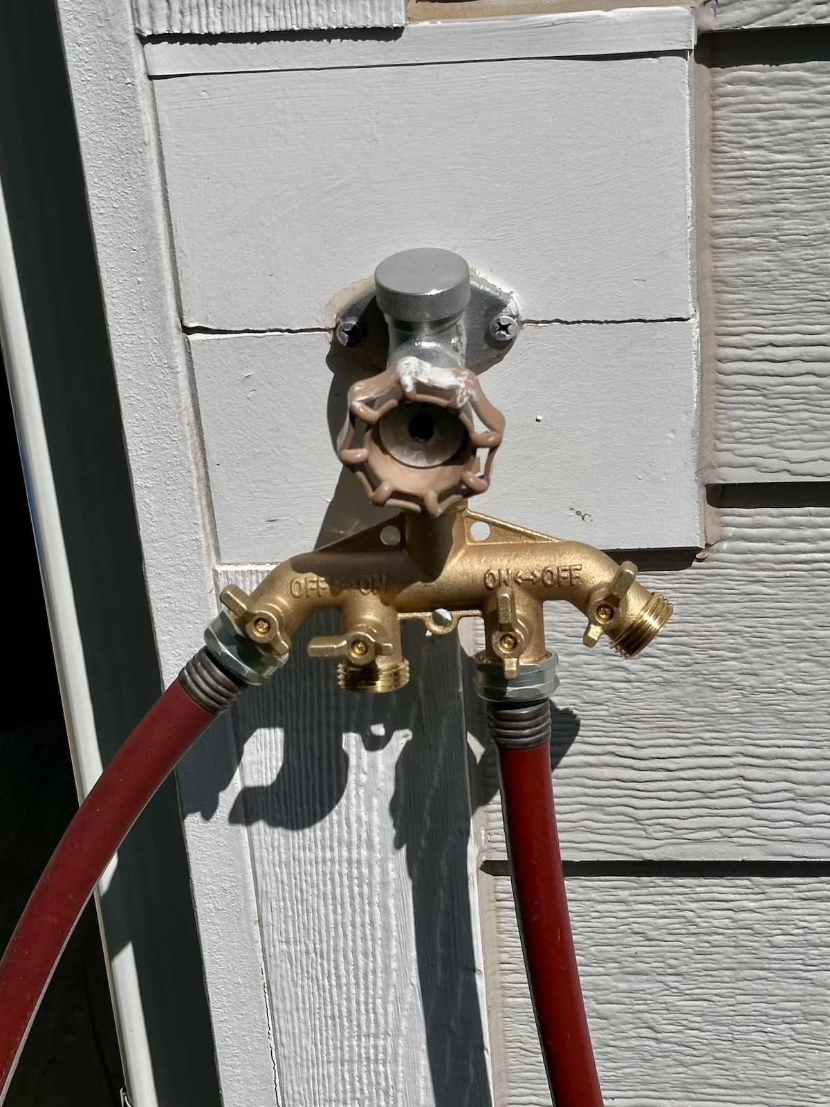 The Twinkle Star Heavy-Duty Brass Garden Hose Splitter hooked up to an outdoor faucet during testing