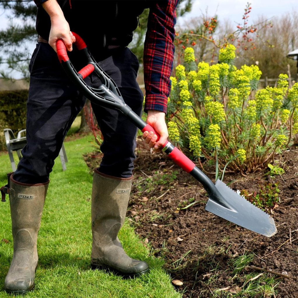 A person using the Roamwild multi-digger spade in a landscape bed