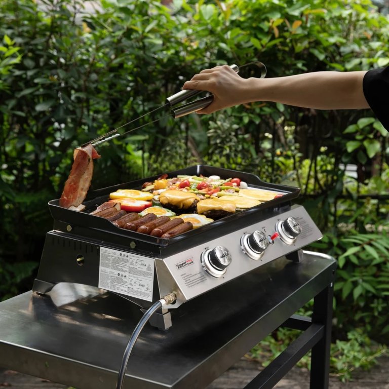 A person cooking various meat and vegetables on the Royal Gourmet portable propane gas griddle