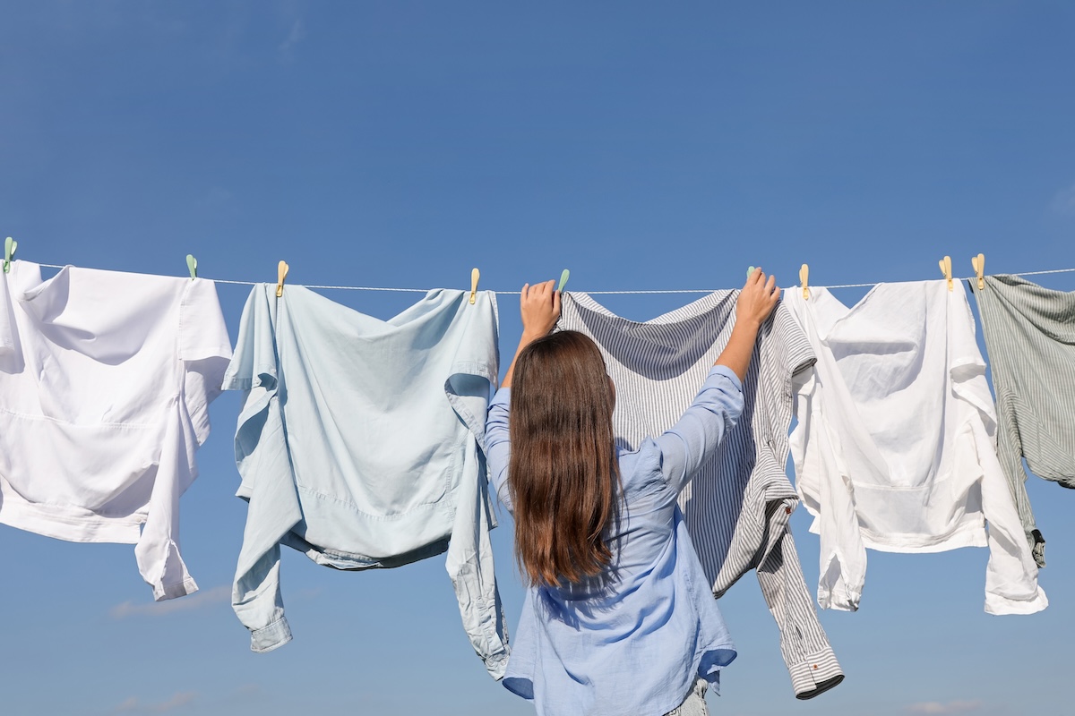 A woman hangs laundry to dry on a clothes line.