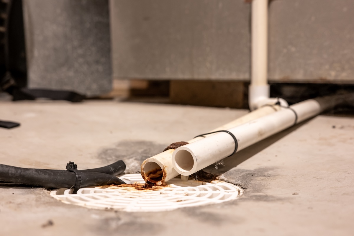 The drain lines of an air conditioning unit rest in a drain.