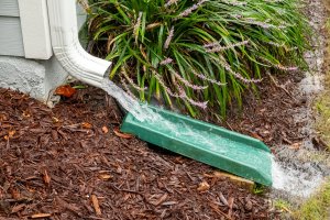 Water gushes from downspout on house during a heavy rainstorm.