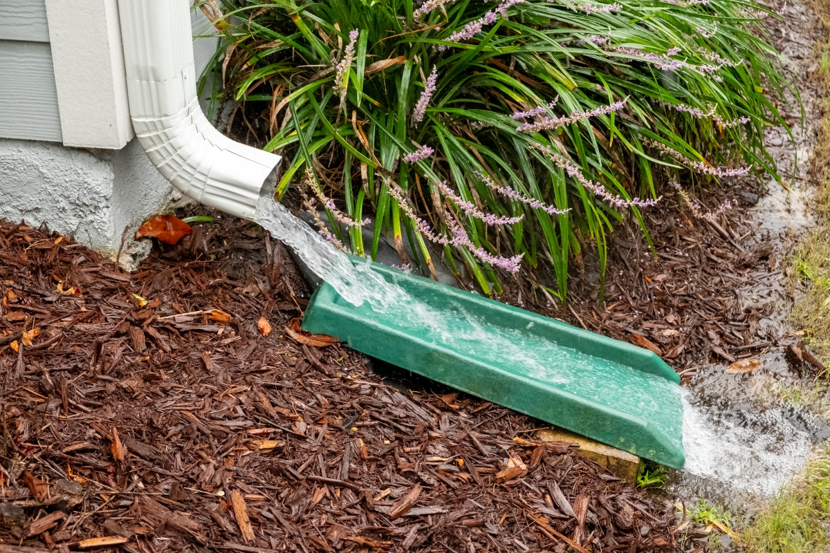 Water gushes from downspout on house during a heavy rainstorm.