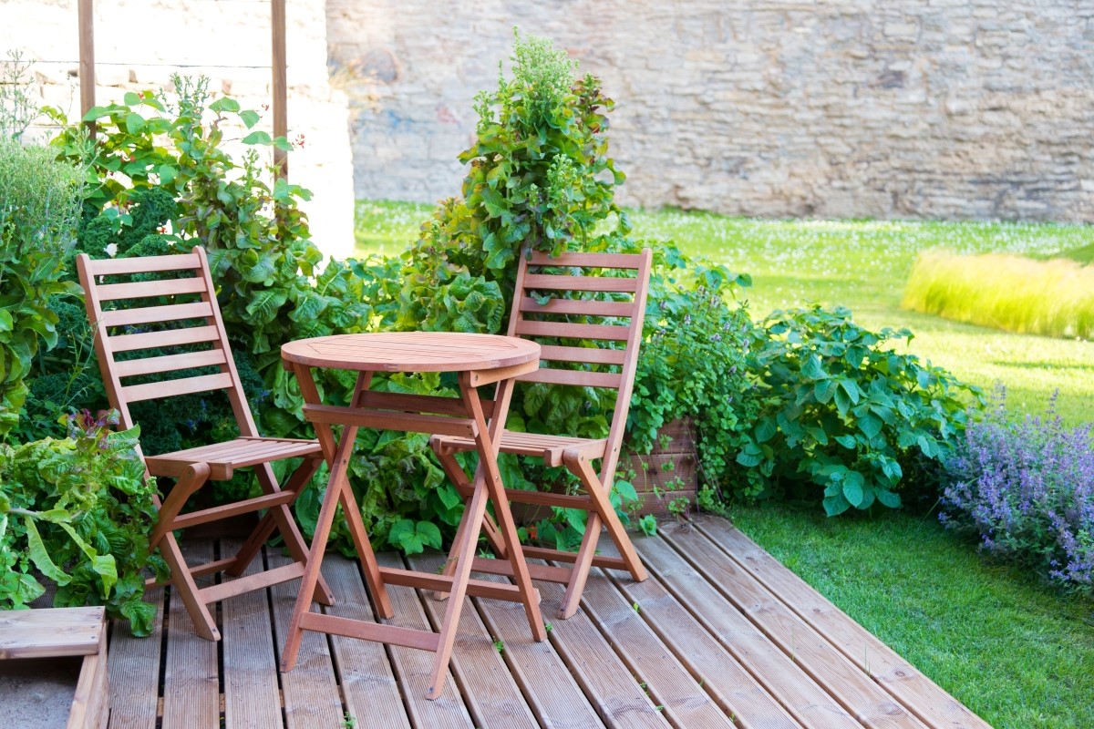 Empty wooden table and chairs on outdoor terrace during summer day.