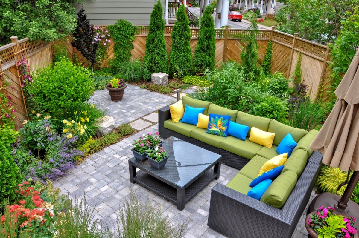 A beautiful small, urban backyard garden featuring a tumbled paver patio, flagstone stepping stones, and a variety of trees, shrubs and perennials add color and year round interest.