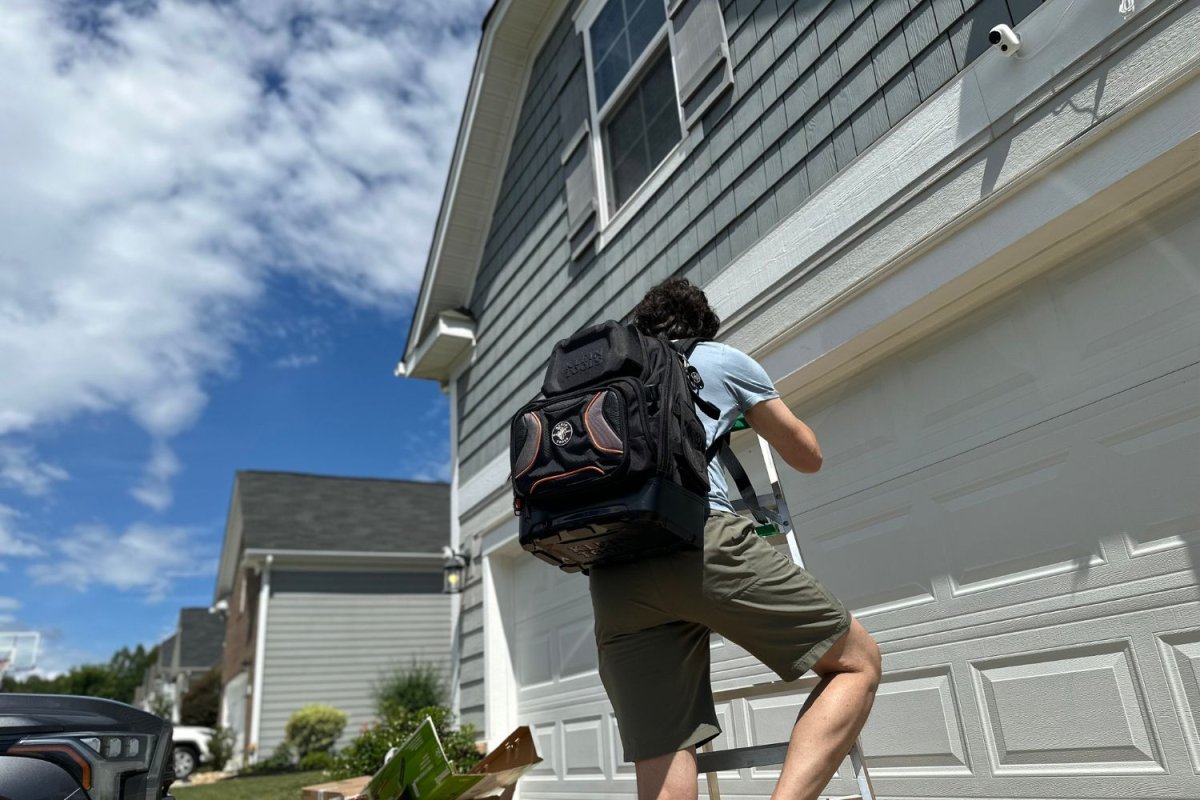 A product tester wearing the Klein Tools Tradesman Pro Tool Backpack while climbing a ladder