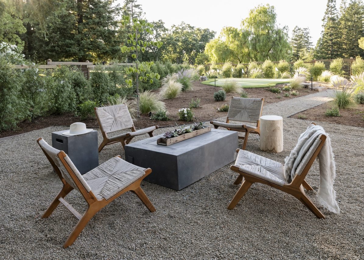 Chairs around fire pit sitting on top of gravel area in backyard