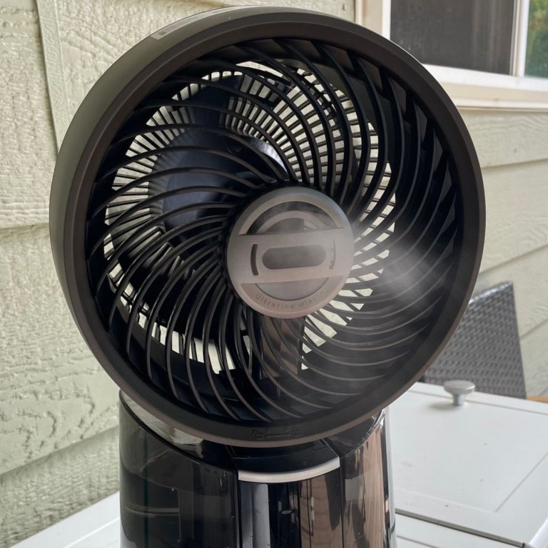 The Dreo 516S TurboCool Misting Fan blowing a cool mist while sitting atop a cooler on a deck
