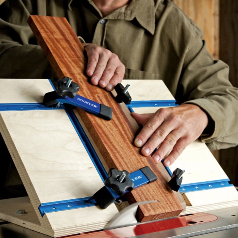 A person using the Rockler Hold Down Clamp to hold a piece of wood in place on a table saw