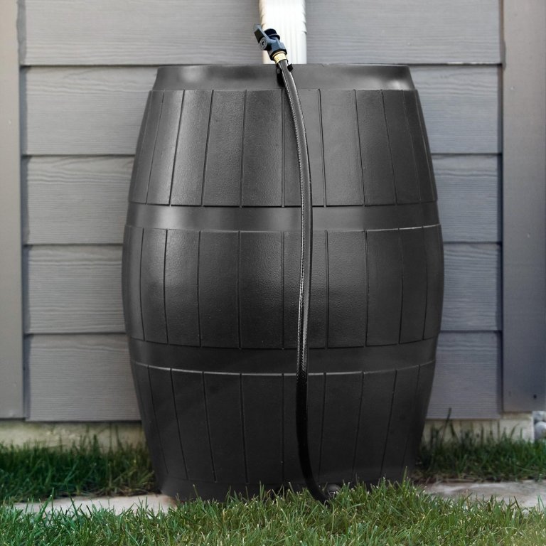 The FCMP Outdoor Raincatcher 4000 rain barrel installed against a house with a downspout behind it