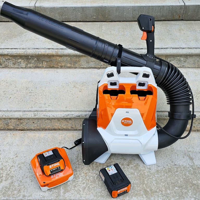 The Stihl Backpack Blower with two atteries and a charger on a set of steps