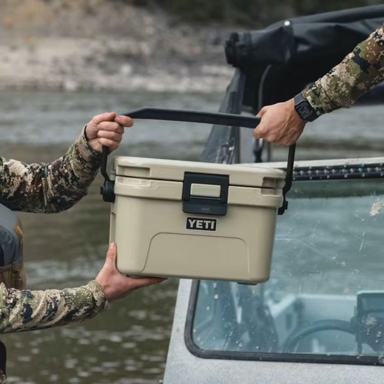 One person hading the Yeti Roadie 8 to another over the side of a boat
