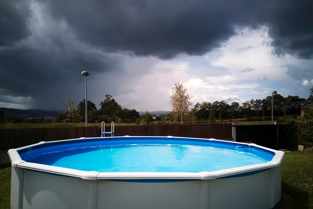An above-ground swimming pool on a stormy day with dark clouds.