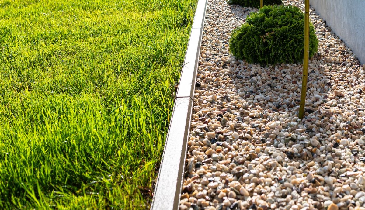 Gravel path separating a lush green lawn from the house exterior