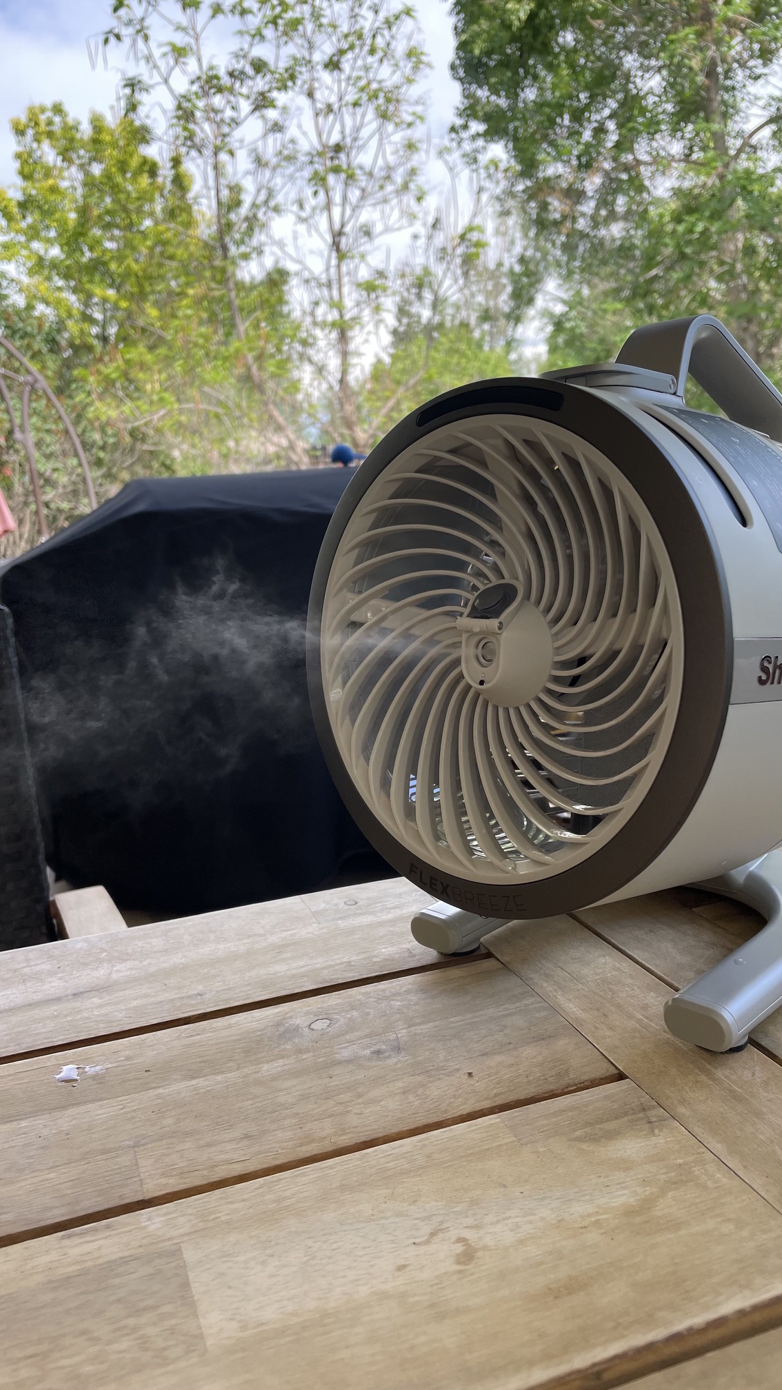 The mister on the Shark FlexBreeze HydroGo Pro Fan shooting a fine mist over an outdoor table