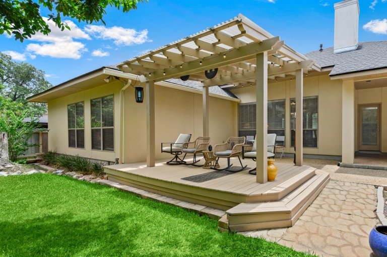 A lovely back deck with a table and pergola