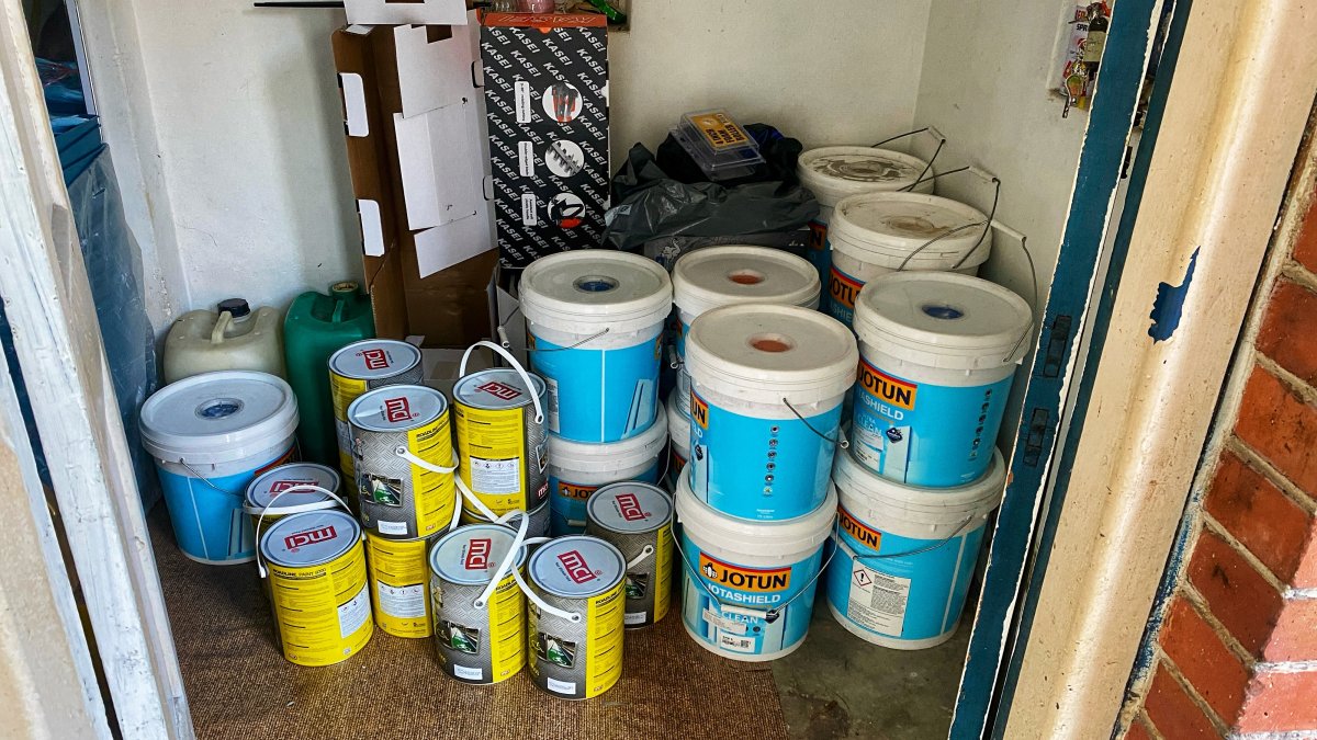 Various paint cans are stored in a store room.