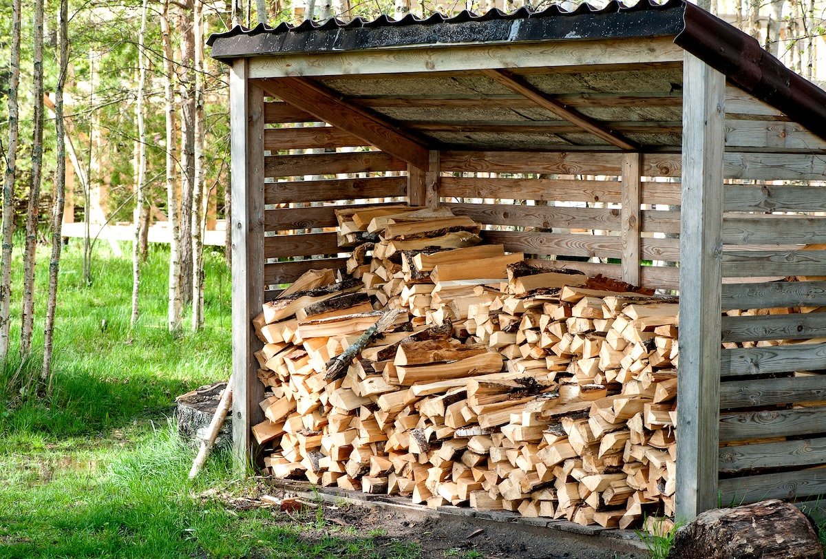 Stack of firewood contained in a covered shed.