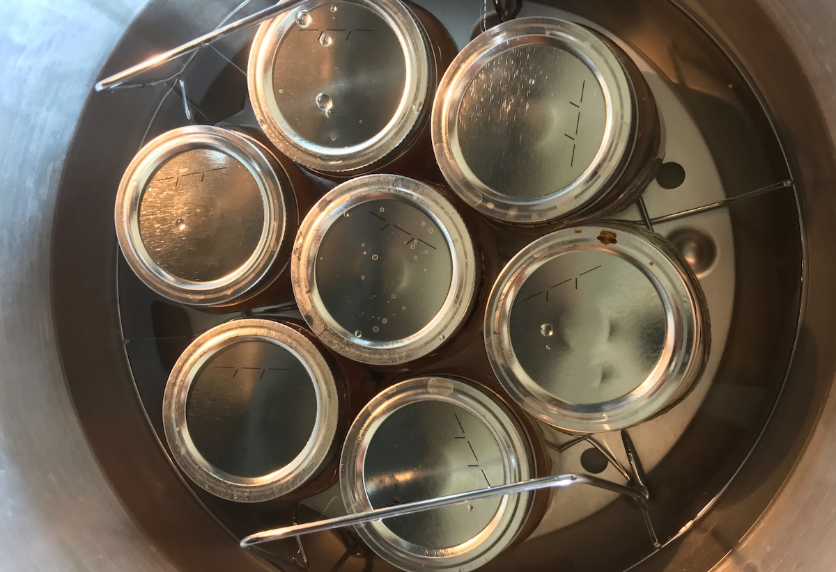 Birds' eye view of canning jars with metal lids, in a pot of water.