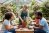 A gardener is teaching a class of adults how to pot a plant.