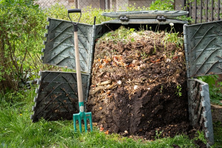 Layers of rotting compost in plastic composter bin in garden.