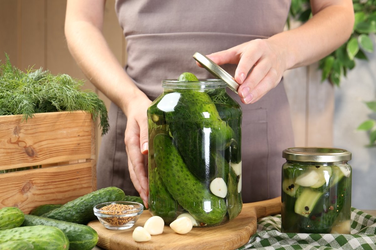 Woman making pickled cucumbers at table.
