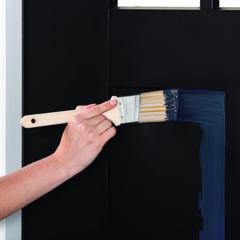 A person brushing Rust-Oleum Advanced Dry Door & Trim Paint onto a front door