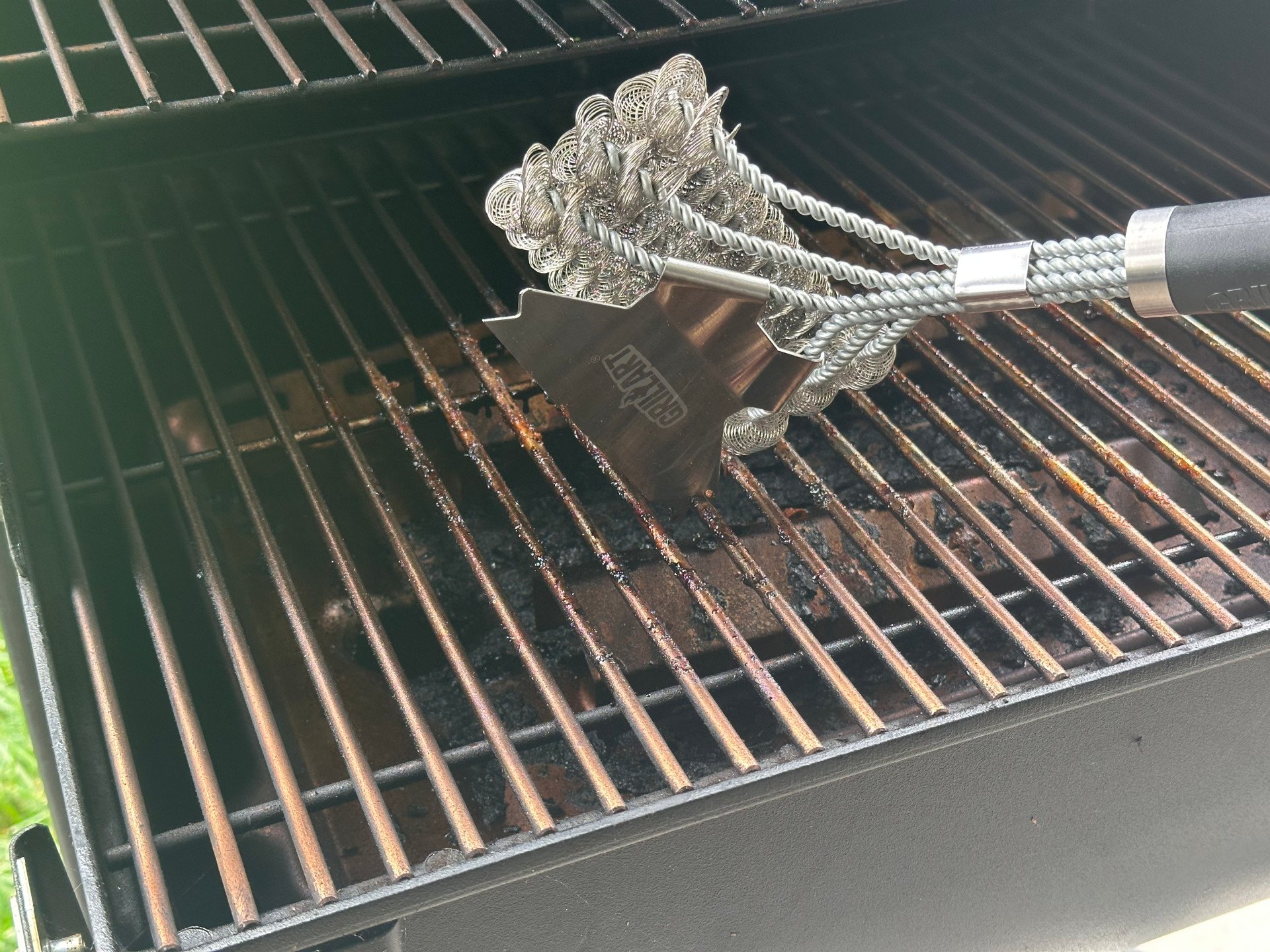 Scraping dirty grill grates with the GrillArt Bristle-Free 17-Inch Brush and Scraper