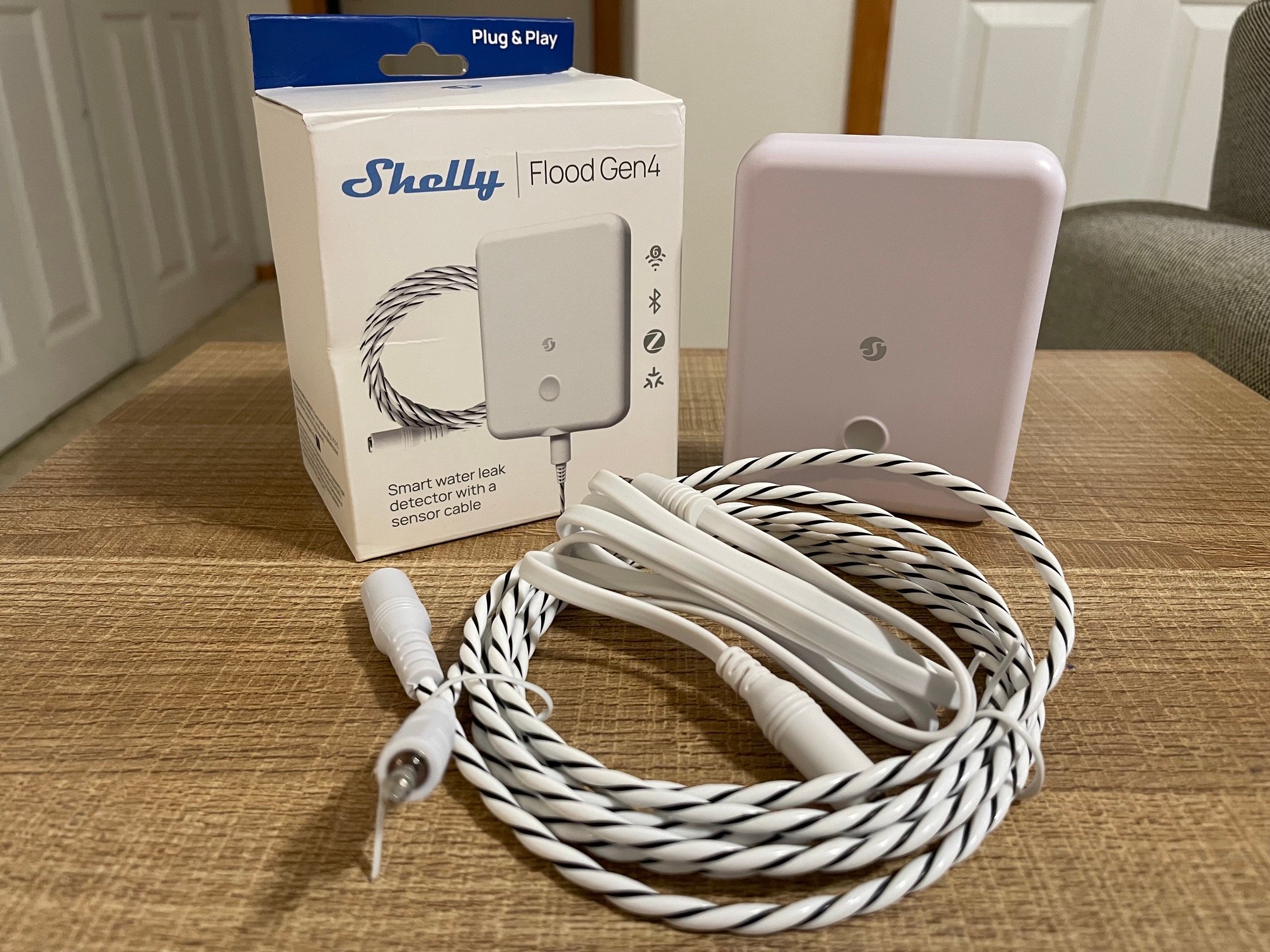 The Shelly Flood Gen4 Smart Water Leak Detector on a table before installation and testing