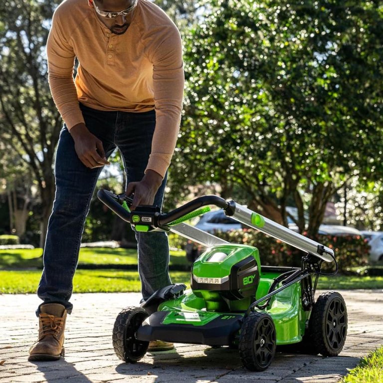 A person folding the handle of the Greenworks 80V 21 Cordless 4-in-1 Push Lawn Mower for easy storage