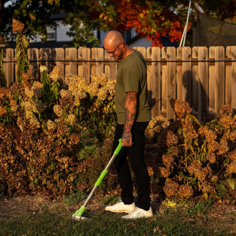 A person pulling a weed in their yard using the GrootPow WP5 Weed Remover Tool