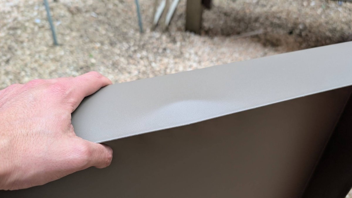 A product tester holding one of the metal trays on the Vego Garden potting cart during assembly