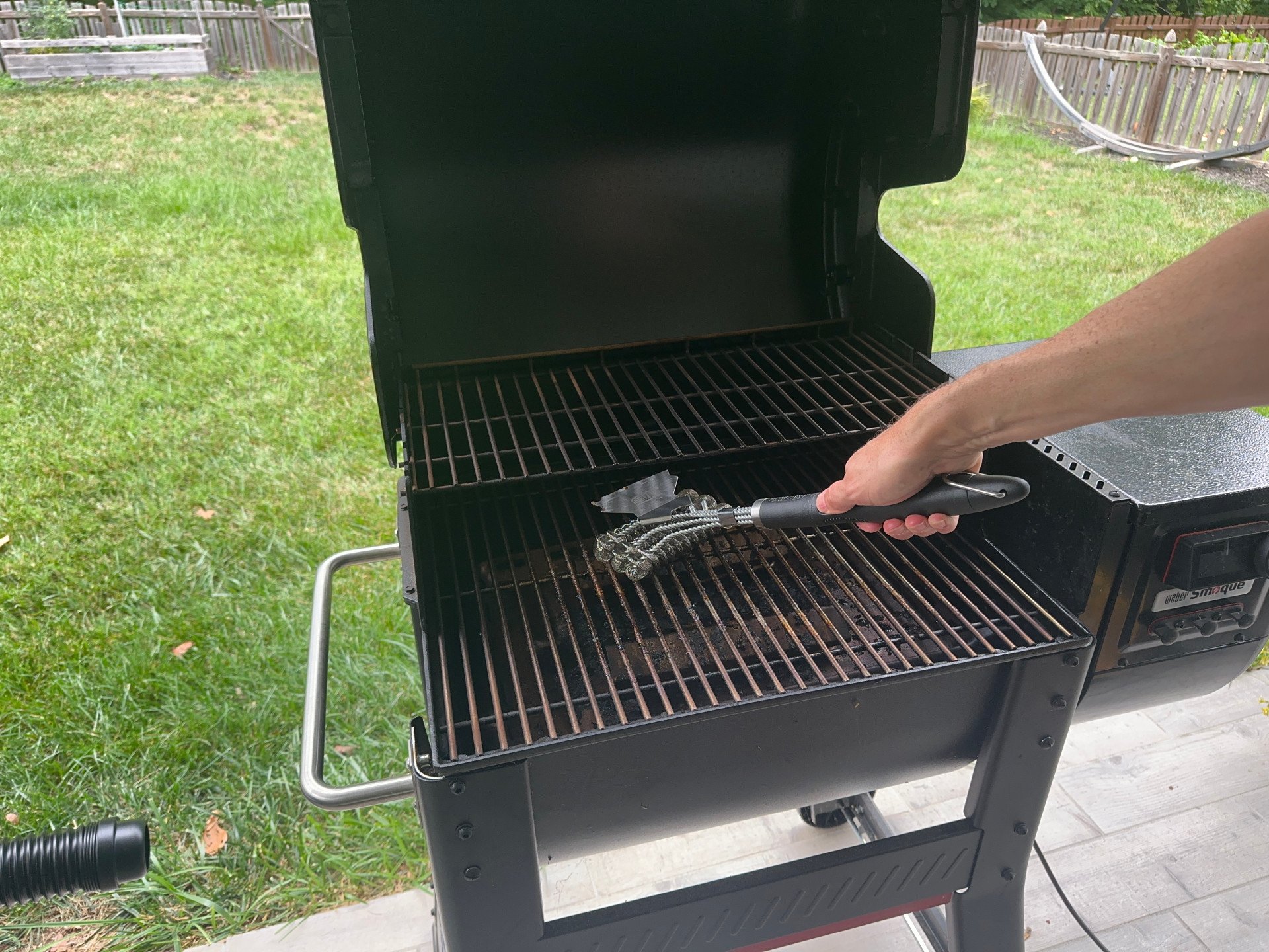 A product tester using the GrillArt Bristle-Free 17-Inch Brush and Scraper to clean a dirty grill