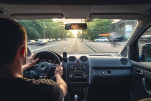A male driver drives at speed through the streets of the city, a view from inside the car.