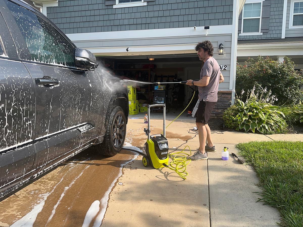 A product tester using one of the best ryobi pressure washers to wash soap off a truck