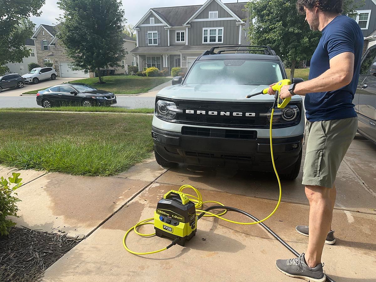 A product tester using one of the best ryobi pressure washers to wash a car