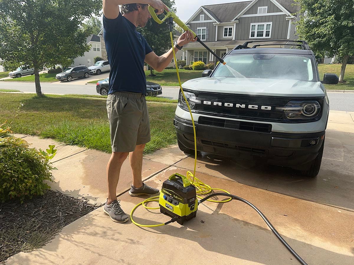 A product tester using one of the best ryobi pressure washers to wash the hood of a car