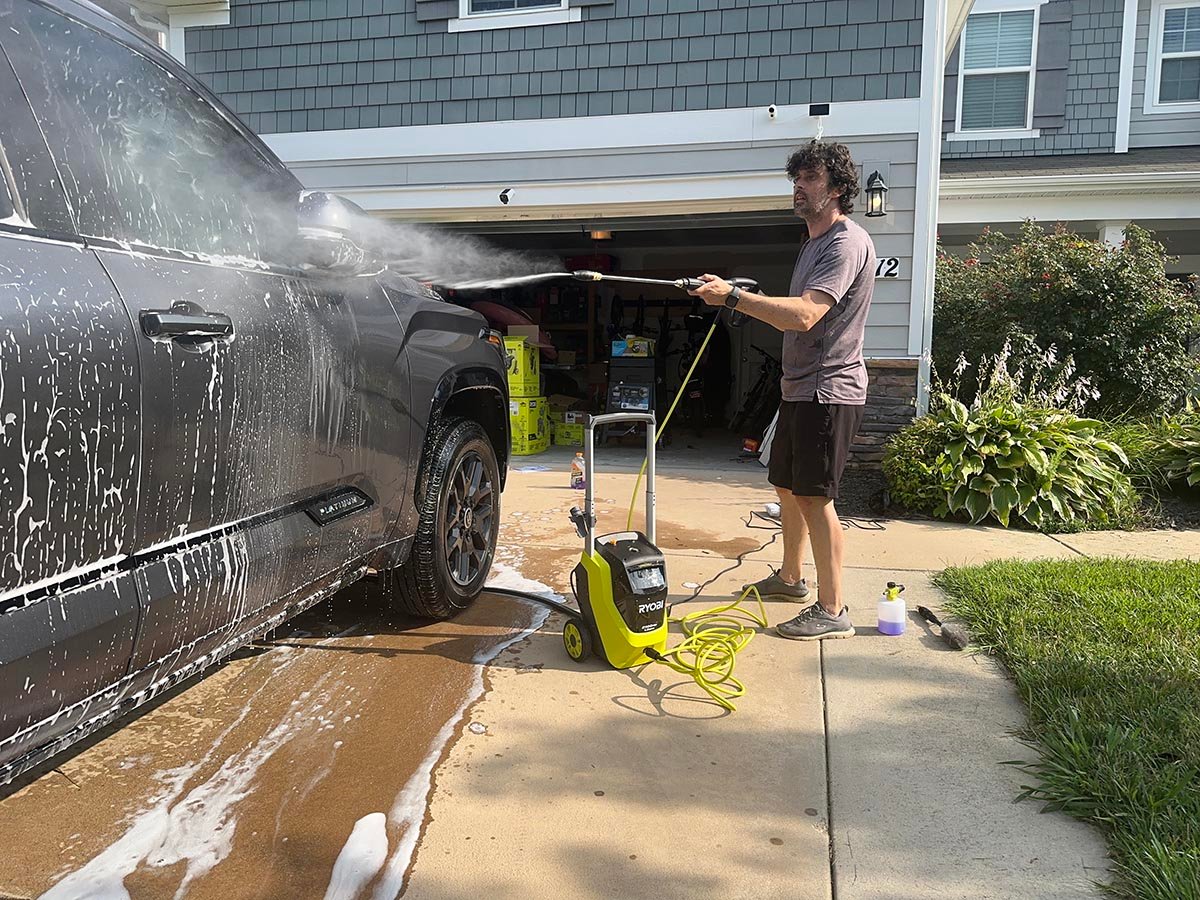 A product tester using one of the best ryobi pressure washers to wash soap off a truck