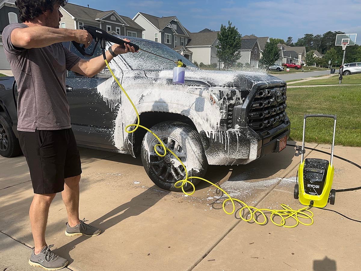 A product tester using one of the best ryobi pressure washers to apply soap to a truck
