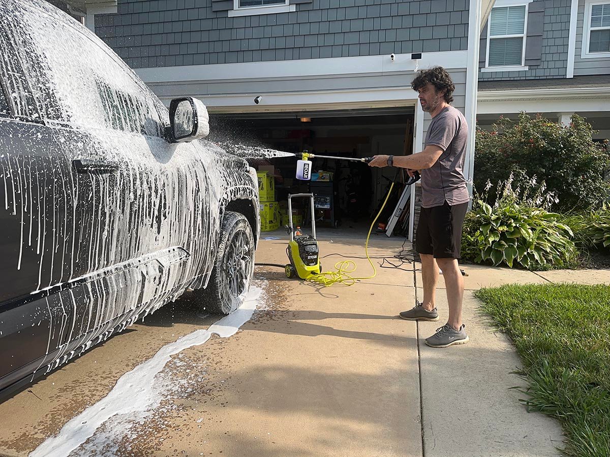 A product tester using one of the best ryobi pressure washers to apply soap to a truck