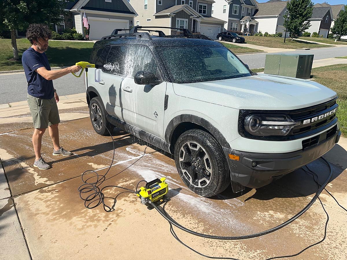 A product tester using one of the best ryobi pressure washers to wash a car